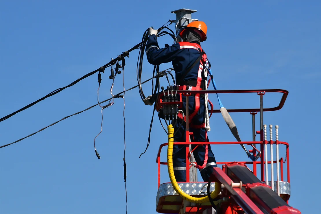 Especialista usando luvas isolantes elétricas e equipado com EPI para trabalho em altura